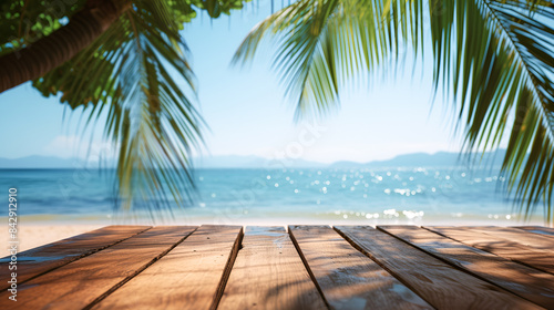 Wooden tabletop against the backdrop of the blue sea and white sand beach. Coconut palms against the background of blue sky and beautiful beach