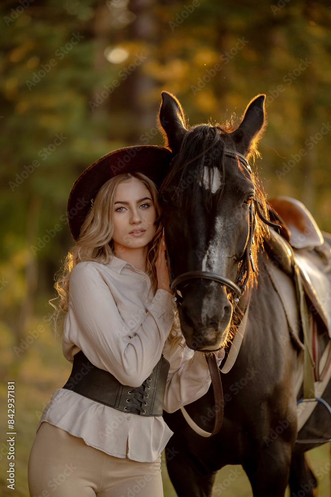 Obraz premium A young beautiful woman walks with her horse in the forest in early autumn. Walking with a horse in the forest.