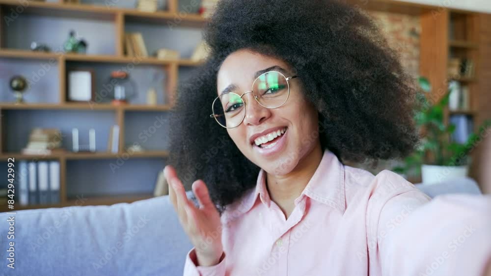 POV A young happy pretty african american female in glasses talking on a video call taking a selfie using a smartphone in home A smiling black woman student has online chat with a friend or boyfriend
