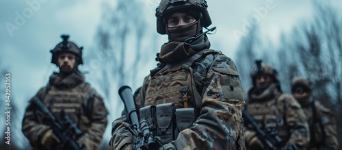 Soldiers in full combat gear stand with their weapons