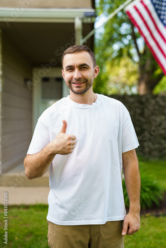 Young handsome man standing in front of house with thumbs up