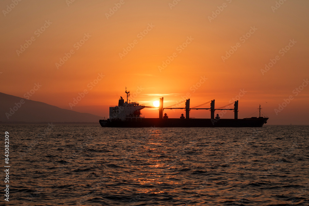 A sunset over the sea with the silhouette of a mountain and a ship. A sunset over the sea with the silhouette of a mountain and a ship.