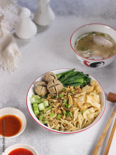 Mie ayam (noodles with chicken, meatballs, dumplings and vegetables) is a popular street food in Indonesia. Blurred background. Close up. Selective focus