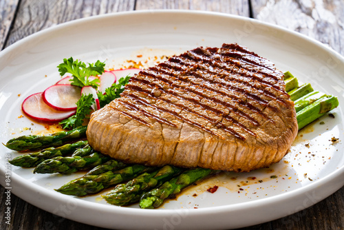 Grilled beef steak with green asparagus on wooden table 