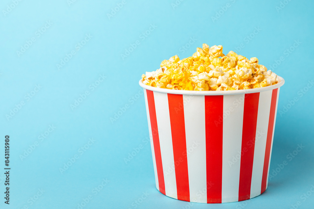 Popcorn box. Red and white striped buckets of popcorn on a blue background. Cinema and entertainment concept. Movie night with popcorn. Cheesy popcorn. Delicious appetizer, snack. Place for text. Popcorn box. Red and white striped buckets of popcorn on a blue background. Cinema and entertainment concept. Movie night with popcorn. Cheesy popcorn. Delicious appetizer, snack. Place for text.