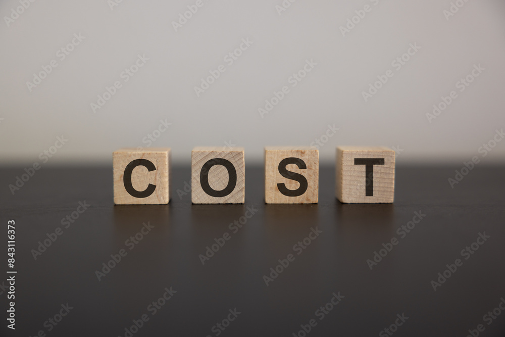 COST word on wooden cube block with green down arrow including copy space COST word on wooden cube block with green down arrow including copy space