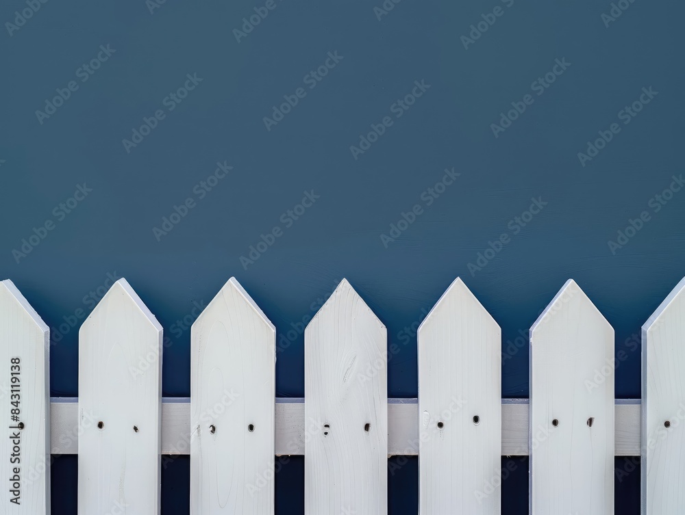 White picket fence against a blue wall White picket fence against a blue wall