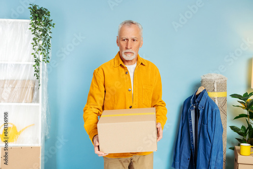 Sad senior mature old man holding cupboard box at home