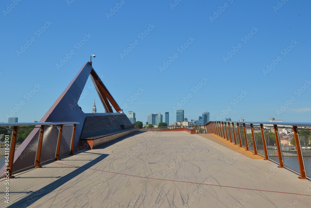 Fototapeta premium New brigde in Warsaw, Poland. Pedestrian and bicycle footbridge over the Vistula River. Warsaw skyline