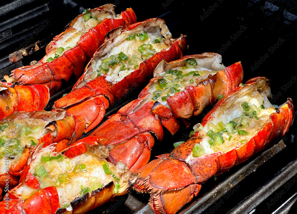 Grilled Lobster Tails with Garlic Lemon Butter Sauce Topped with Green Onions. Closeup Pictures During Preparation and Grilling. Summer Seafood Barbecue Grilled Lobster Tails with Garlic Lemon Butter Sauce Topped with Green Onions. Closeup Pictures During Preparation and Grilling. Summer Seafood Barbecue