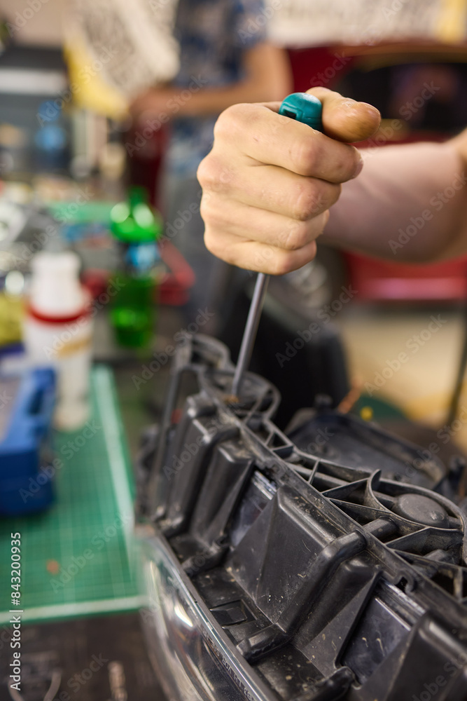 showing hands effectively repairing a car headlight in a workshop environment showing hands effectively repairing a car headlight in a workshop environment