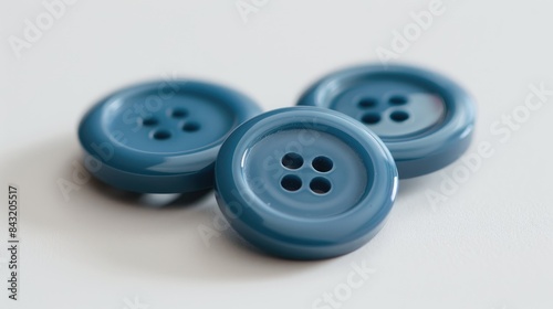 Four blue sewing buttons in a close up arrangement on a white backdrop