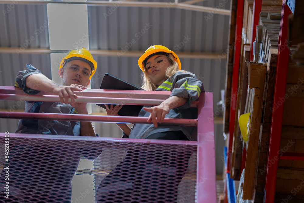 workers man and woman using a hydraulic scissor lift to check stock near the shelves warehouse. industry factory warehouse. Worker Screening Package In Warehouse. workers man and woman using a hydraulic scissor lift to check stock near the shelves warehouse. industry factory warehouse. Worker Screening Package In Warehouse.