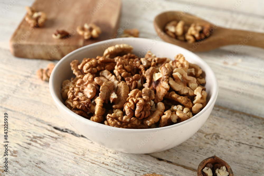 Bowl of tasty walnuts on white wooden background Bowl of tasty walnuts on white wooden background