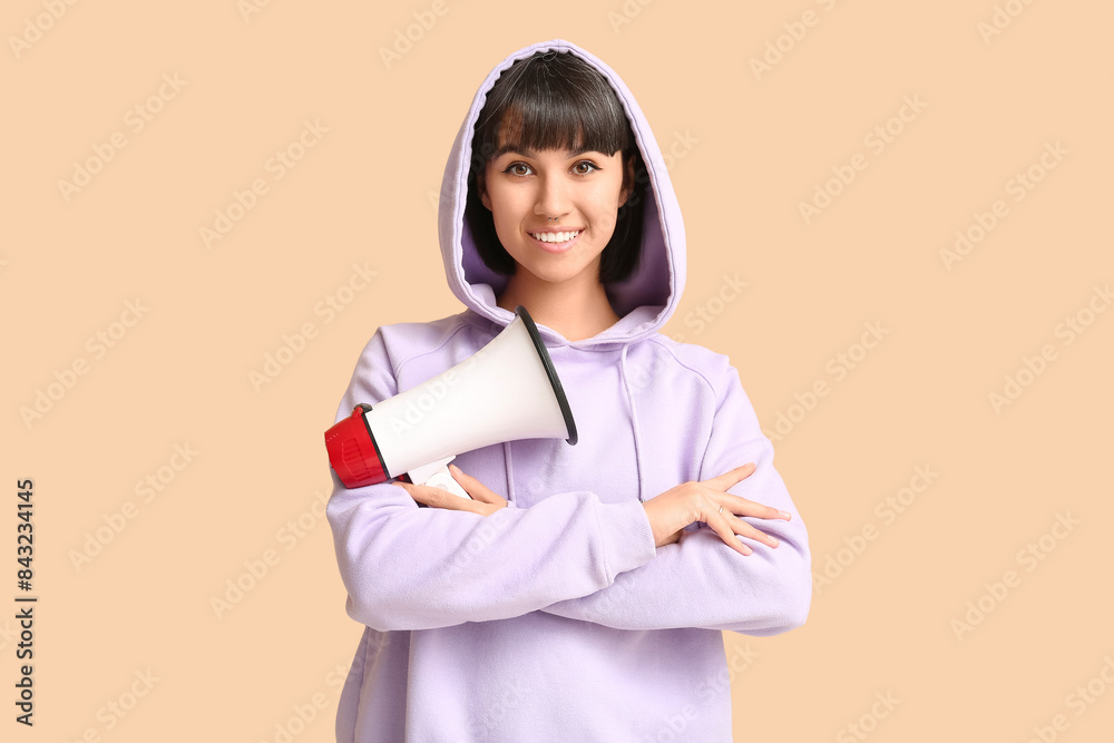 Young woman with megaphone on beige background Young woman with megaphone on beige background