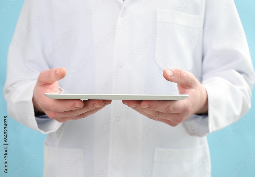 Doctor with tablet on light blue background, selective focus Doctor with tablet on light blue background, selective focus