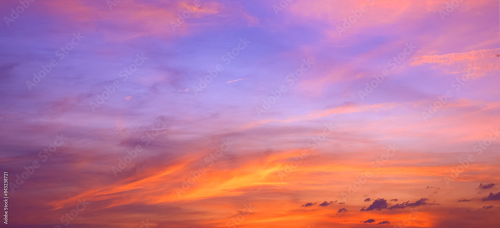 Fototapeta premium Dusk sky background after sundown with colorful orange sunlight clouds on blue evening sky, panoramic view