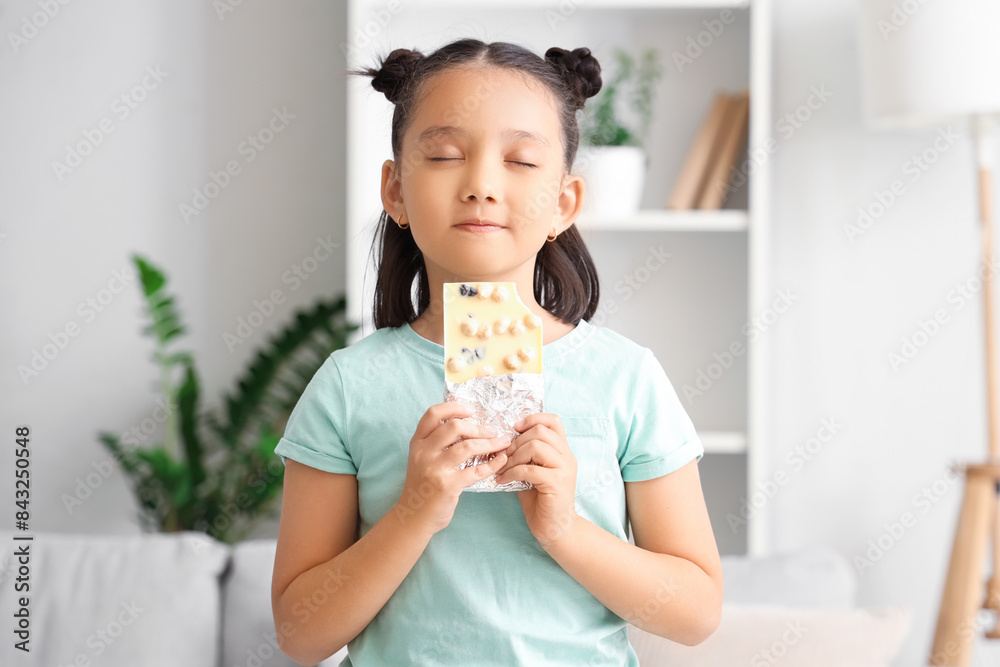 Cute little Asian girl with white chocolate bar at home Cute little Asian girl with white chocolate bar at home
