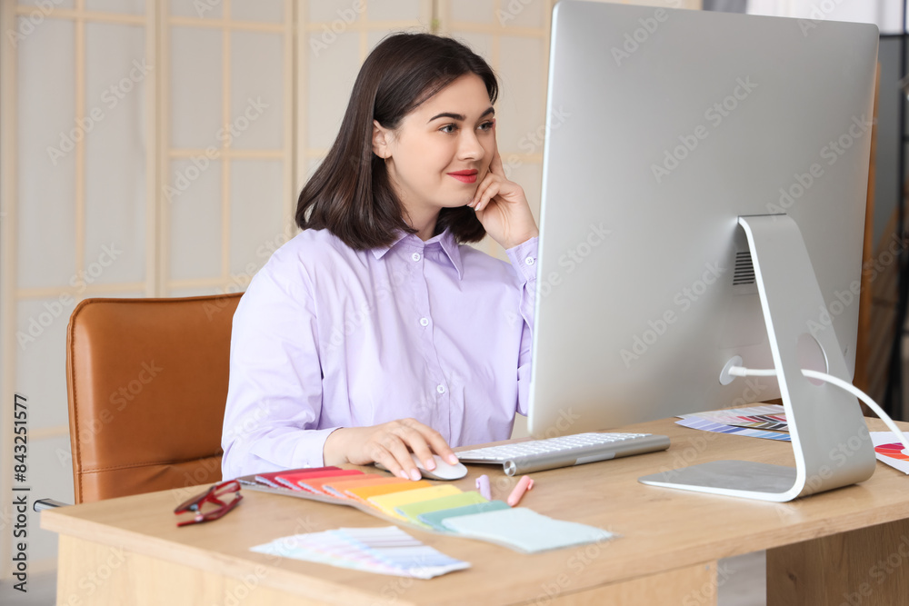 Young interior designer working with computer at table in office Young interior designer working with computer at table in office