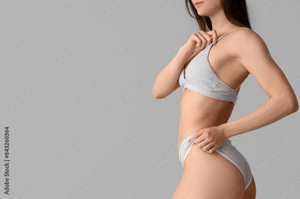 Young woman in underwear on light background