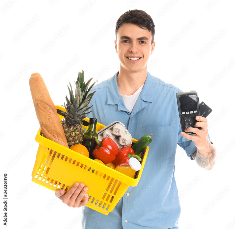 Young man with credit card, payment terminal and full shopping basket on white background Young man with credit card, payment terminal and full shopping basket on white background