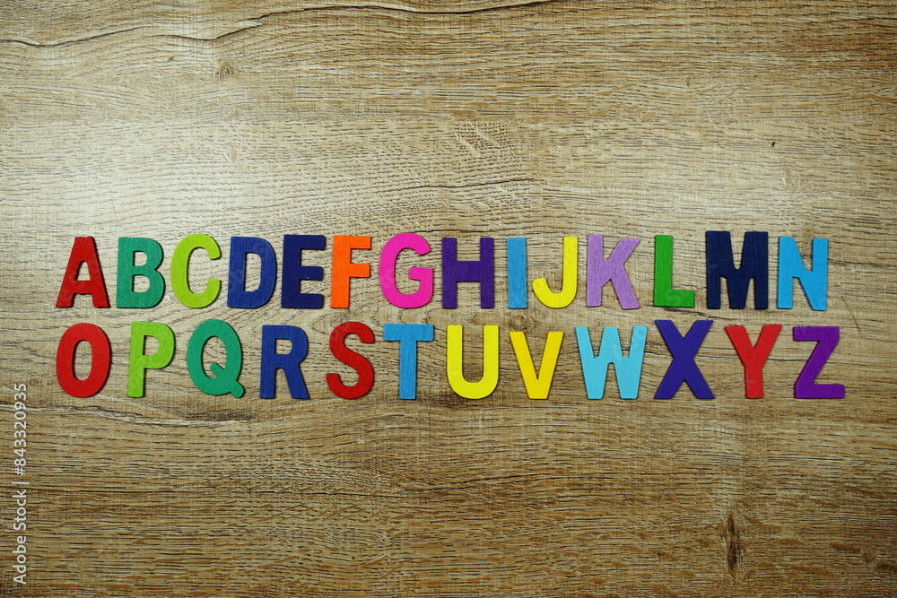 Fototapeta premium Colorful letterpress alphabet with space copy top view on wooden background