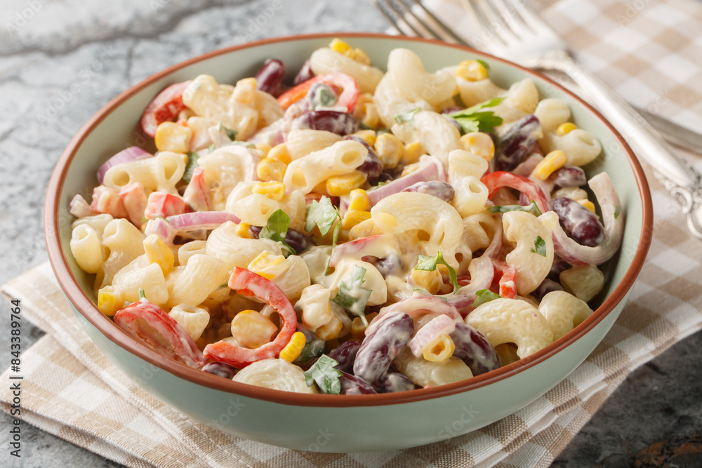 Delicious American macaroni pasta salad with onions, corn, beans, peppers with ranch dressing close-up in a bowl on the table. Horizontal Delicious American macaroni pasta salad with onions, corn, beans, peppers with ranch dressing close-up in a bowl on the table. Horizontal