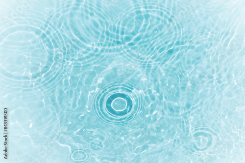 Blue water with ripples on the surface. Defocus blurred transparent blue colored clear calm water surface texture with splashes and bubbles. Water waves with shining pattern texture background.