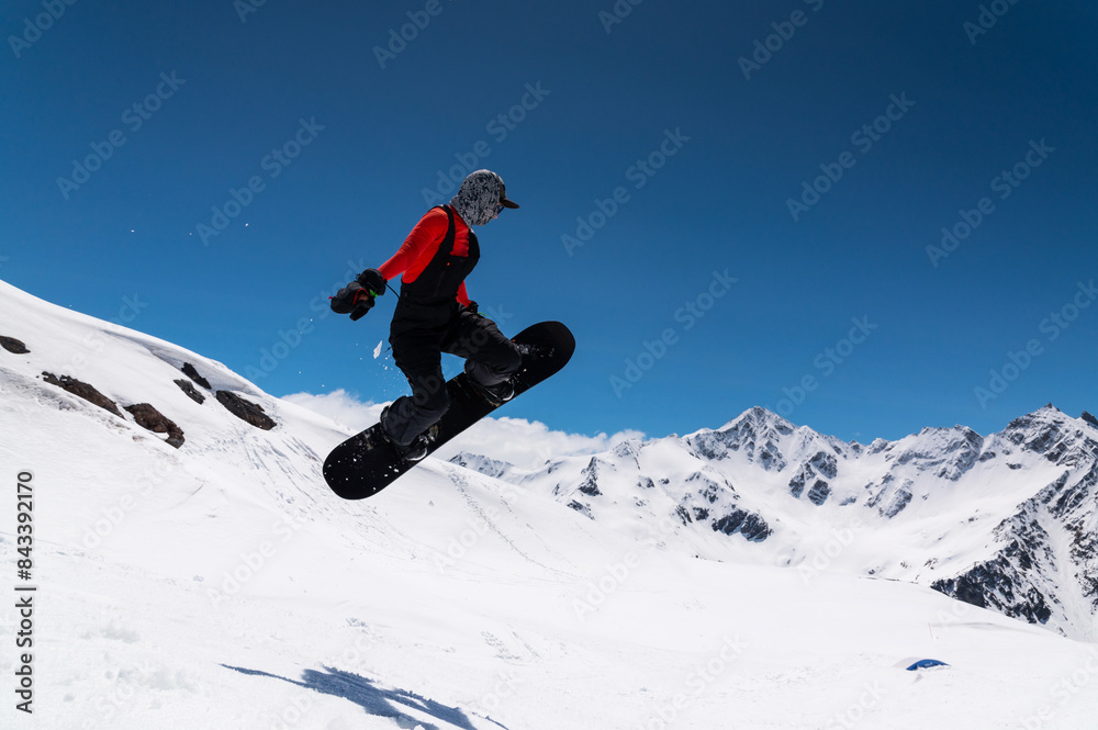 snowboarder in bright sportswear makes a trick against the backdrop of beautiful mountains