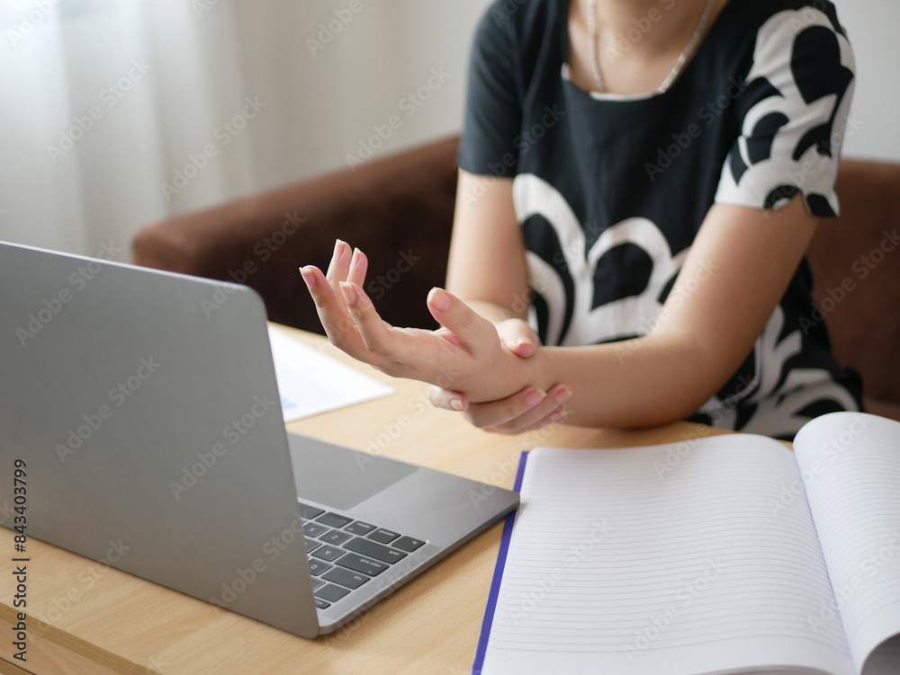 A young Asian woman working at the office feels pain in her wrists from typing from a laptop for a long time. Pain and numbness in the wrist Health care and medical concept A young Asian woman working at the office feels pain in her wrists from typing from a laptop for a long time. Pain and numbness in the wrist Health care and medical concept