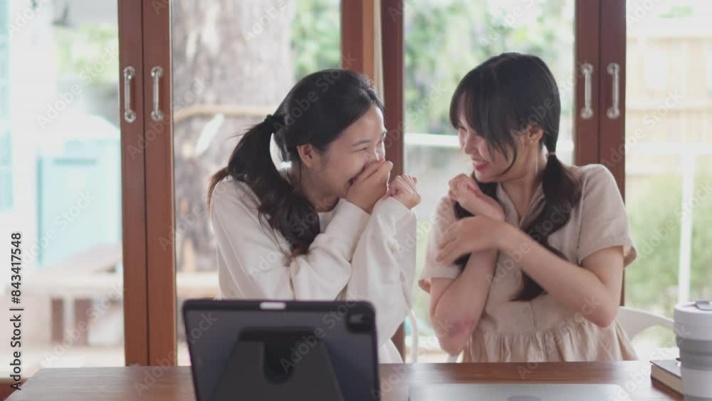 Two Asian female friends are watching a romantic movie on a tablet at home Two Asian female friends are watching a romantic movie on a tablet at home
