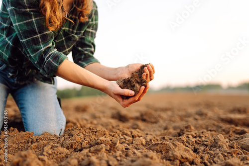 Close up of the female hands touching dry ground in an agricultural field while analyzing soil during the summer day. Business or ecology concept.