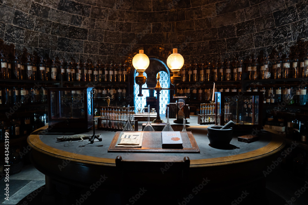 Naklejka premium JAPAN - Nov 13, 2023: Vintage apothecary room with shelves lined of potion bottle laboratory equipment and book on the table at Warner Bros. Studio Tour Tokyo, The Making of Harry Potter