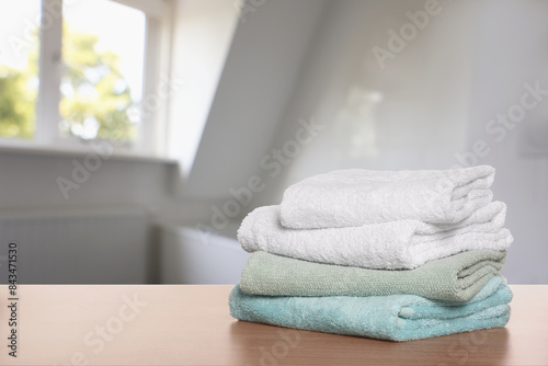 Folded fresh towels on wooden table in bathroom. Space for text