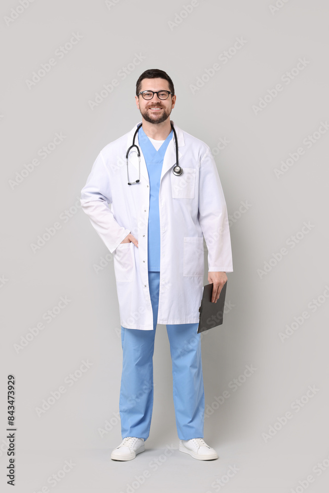 Smiling doctor with clipboard on light grey background Smiling doctor with clipboard on light grey background