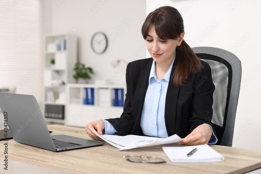 Secretary doing paperwork at table in office Secretary doing paperwork at table in office