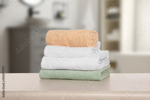 Folded fresh towels on table against blurred bathroom interior