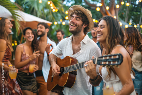 A group of friends dancing and laughing while playing the guitar in an outdoor garden party © Kien