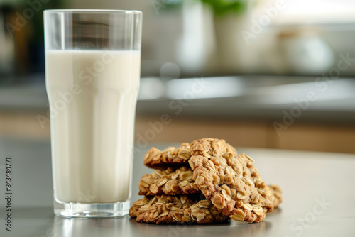A glass of fresh milk with a stack of oat cookies in a cozy kitchen setting, evoking warmth and comfort.