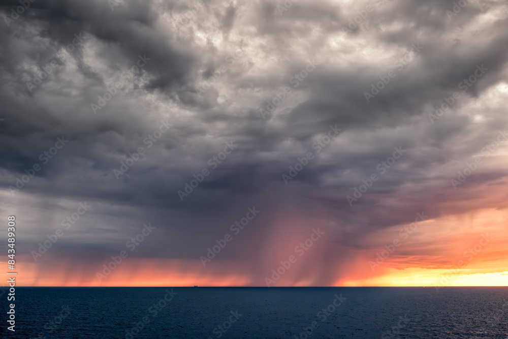 Fototapeta premium A large dramatic storm and falling rain as the sun sets over the Mediterranean sea off the coast of Marseille