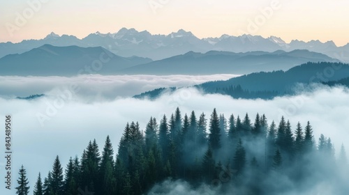 Misty mountains with layers of fog over a forest during sunrise or sunset, creating a serene landscape.