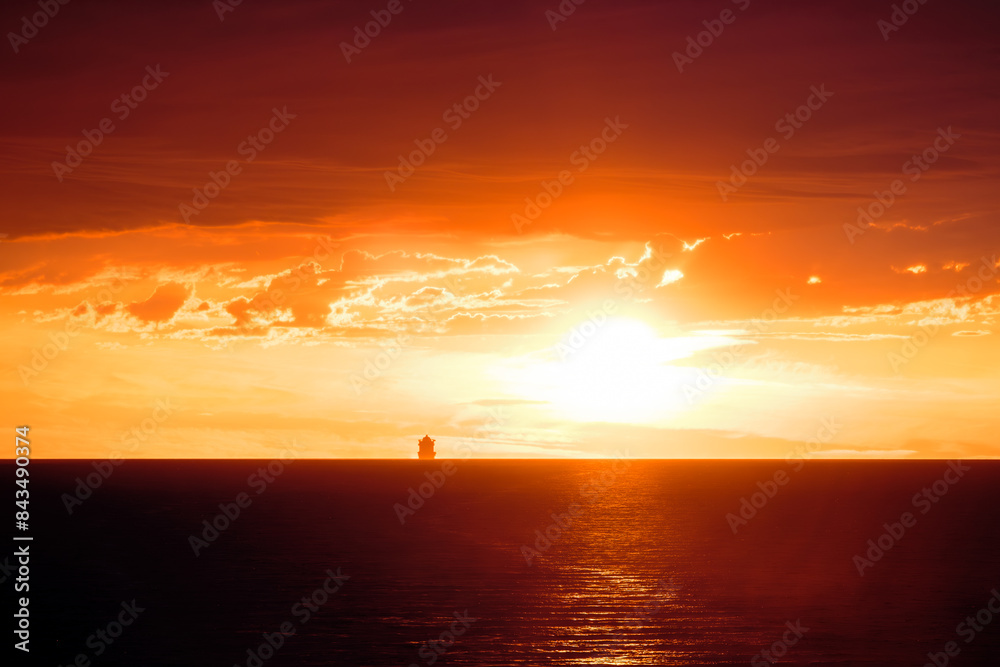 A large ship silhouetted on the horizon of the Mediterranean sea against a dramatic orange sunset A large ship silhouetted on the horizon of the Mediterranean sea against a dramatic orange sunset
