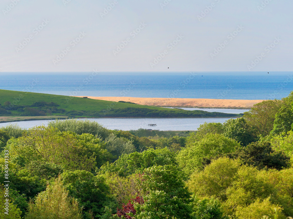 An overview of Abbotsbury village and surrounding fields and Chesil beach from St Catherine`s Hill in Dorset on a sunny morning in May An overview of Abbotsbury village and surrounding fields and Chesil beach from St Catherine`s Hill in Dorset on a sunny morning in May