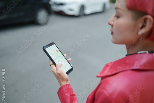 Traveler Gen z girl leather fashion with punk Asian woman tourist in city street searching location in map application online smart phone using GPS navigating