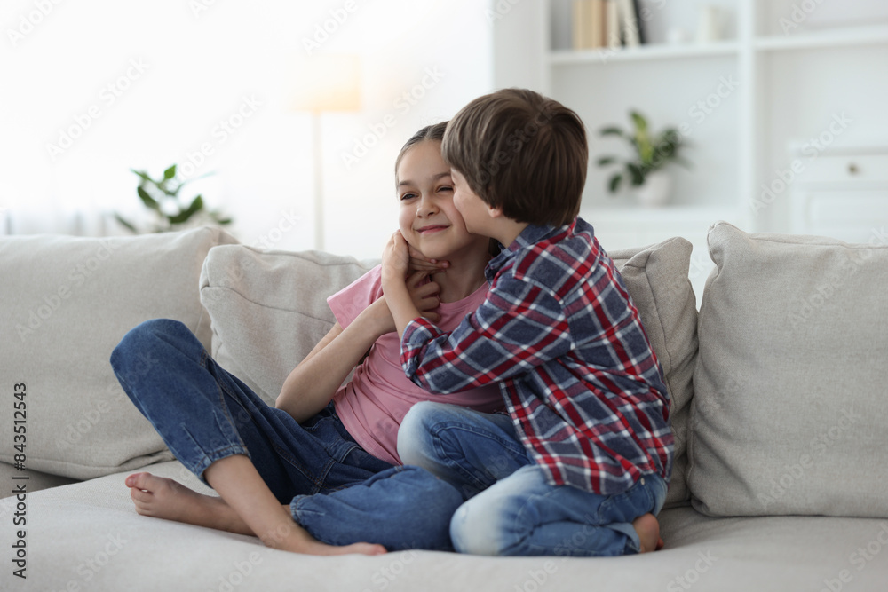 Happy brother and sister spending time together on sofa at home Happy brother and sister spending time together on sofa at home