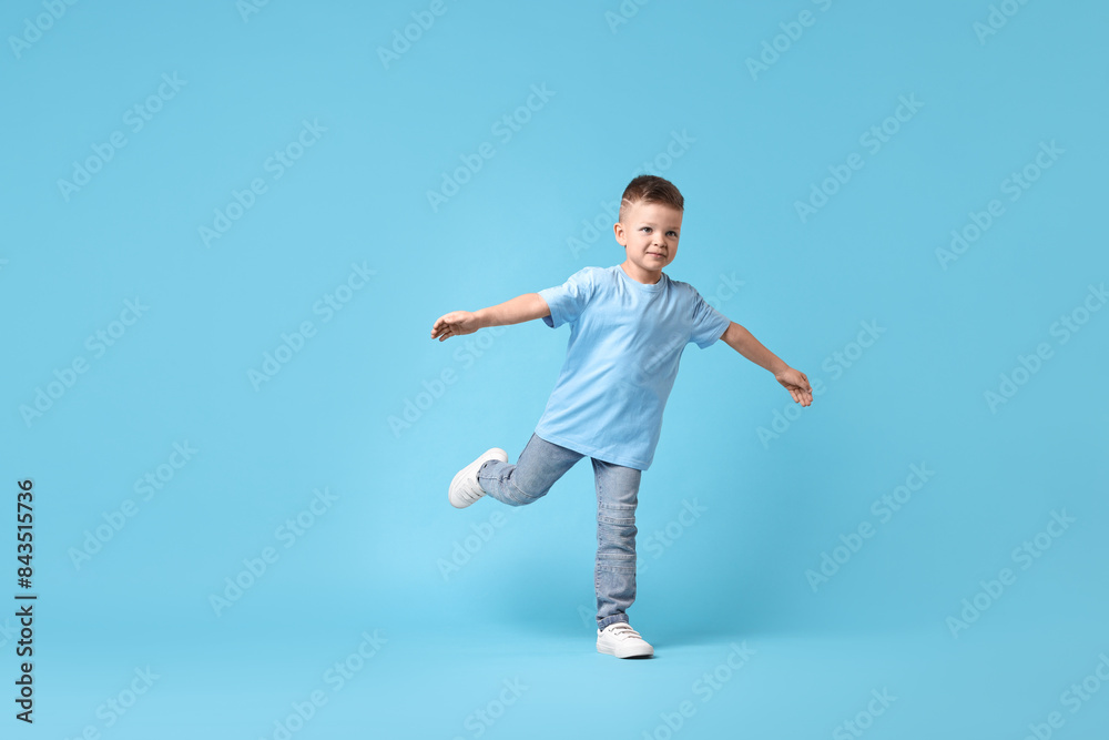 Happy little boy dancing on light blue background Happy little boy dancing on light blue background