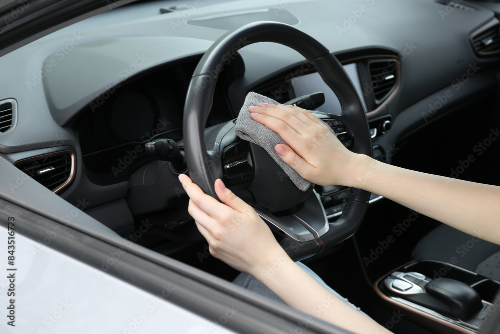 Woman cleaning steering wheel with rag in car, closeup Woman cleaning steering wheel with rag in car, closeup