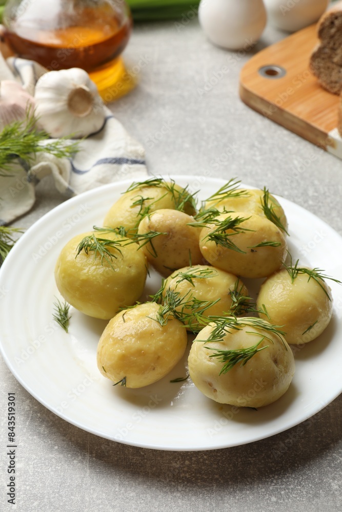 Tasty young boiled potatoes with dill on light grey table Tasty young boiled potatoes with dill on light grey table