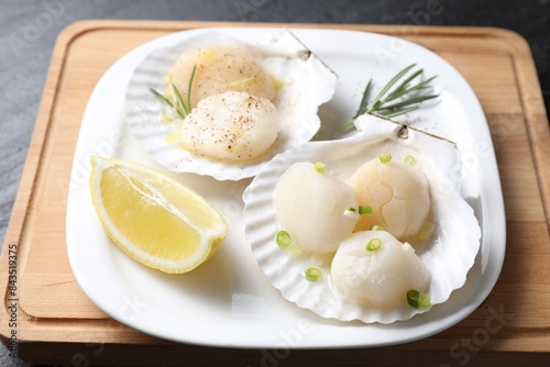 Raw scallops with green onion, rosemary and lemon on dark table, closeup