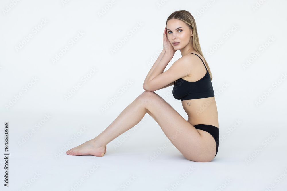 Young woman posing in black lingerie on white studio background with bare feet. Young woman posing in black lingerie on white studio background with bare feet.